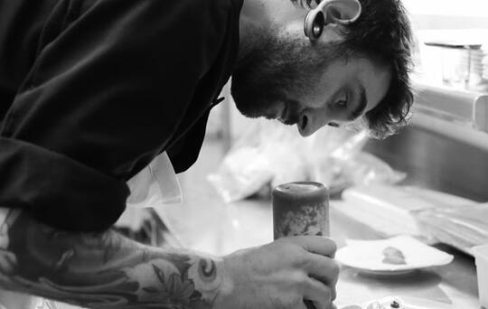 Para captar clientes, los restaurantes rotan sus chefs. En la imagen, un Chef con tatuajes sirve un plato